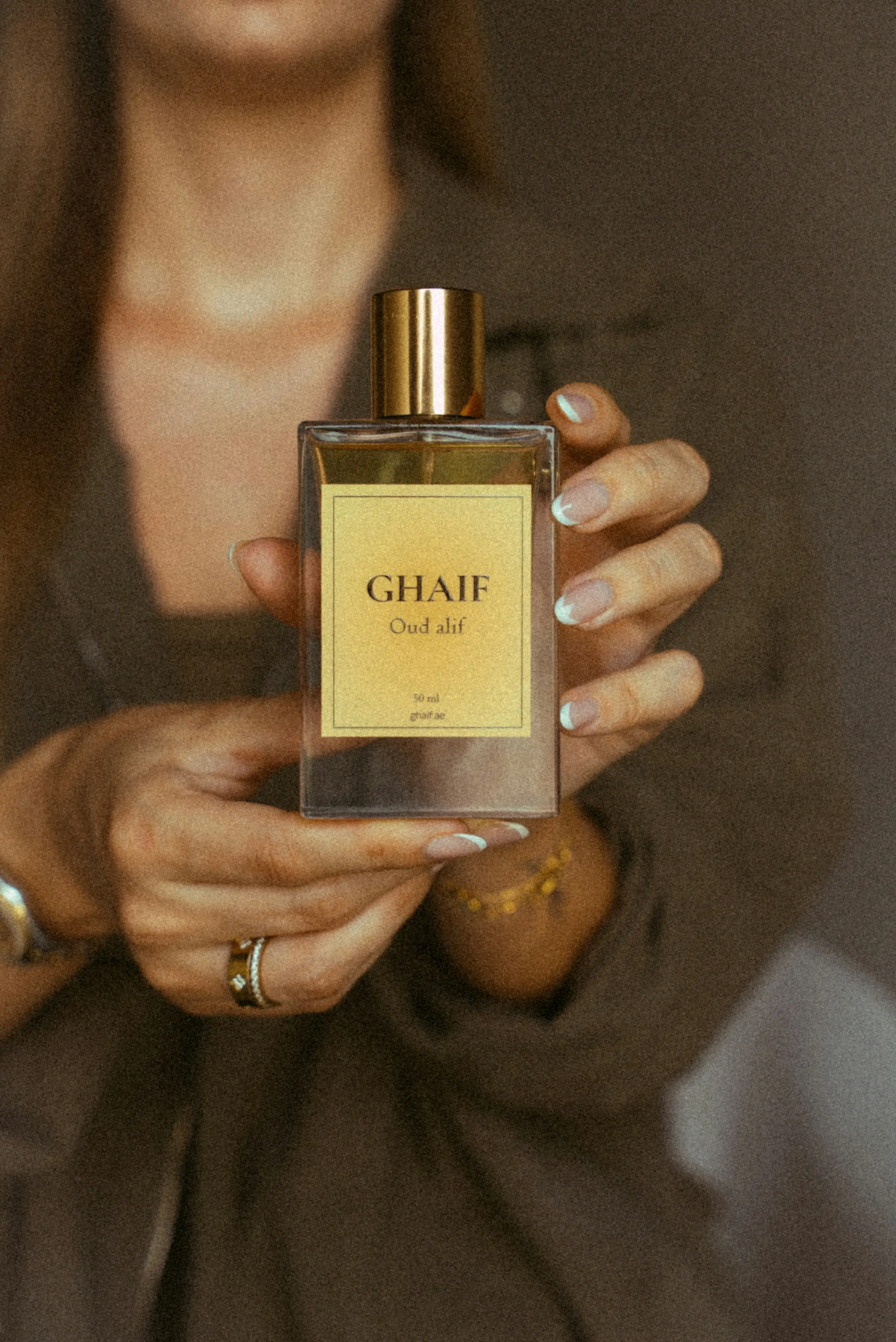 Hands holding a bottle of oud perfume